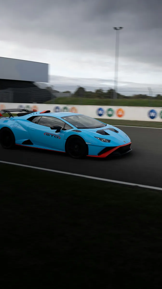 Blue Lamborghini Huracán STO driving on a racetrack